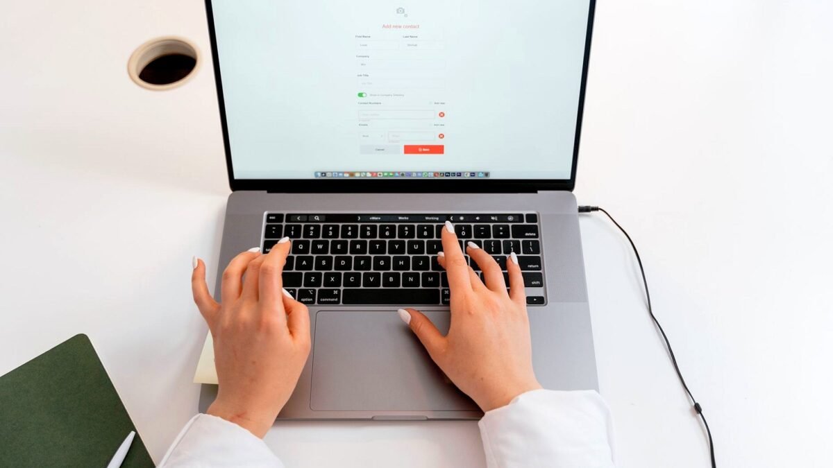 Zbliżenie rąk piszących na klawiaturze laptopa w biurze.