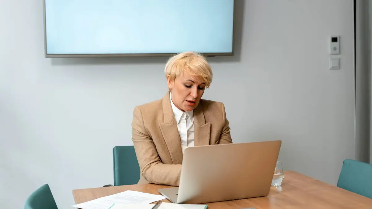 Kobieta przy laptopie czyta odpowiedź asystenta na ekranie, w jasnym biurze