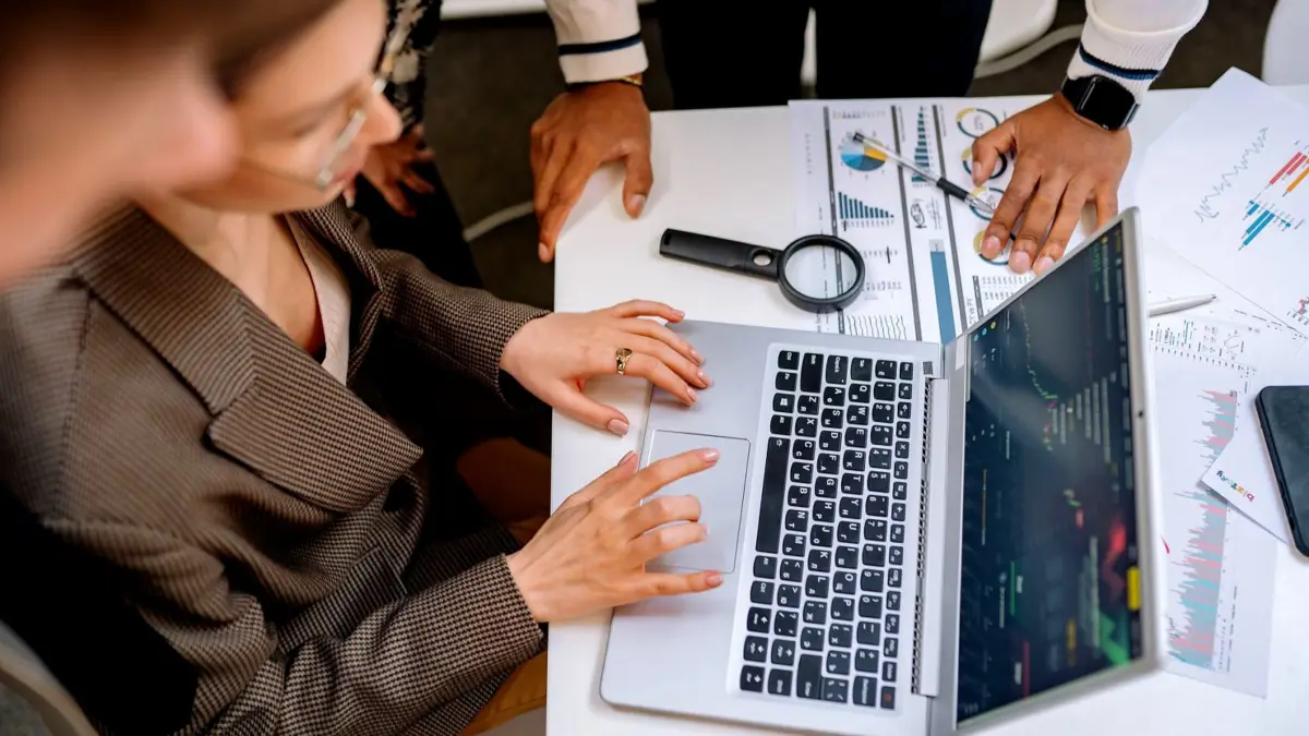Dwie osoby w biurze patrzą na wykresy na ekranie laptopa