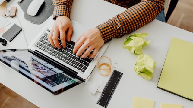 Widok z góry na dłonie piszące na klawiaturze laptopa przy biurku