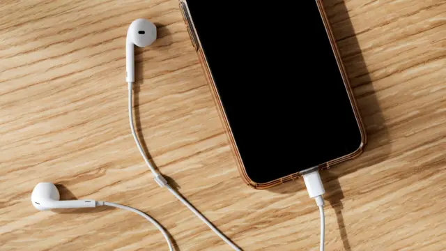 Smartfon i słuchawki leżące na drewnianym blacie
