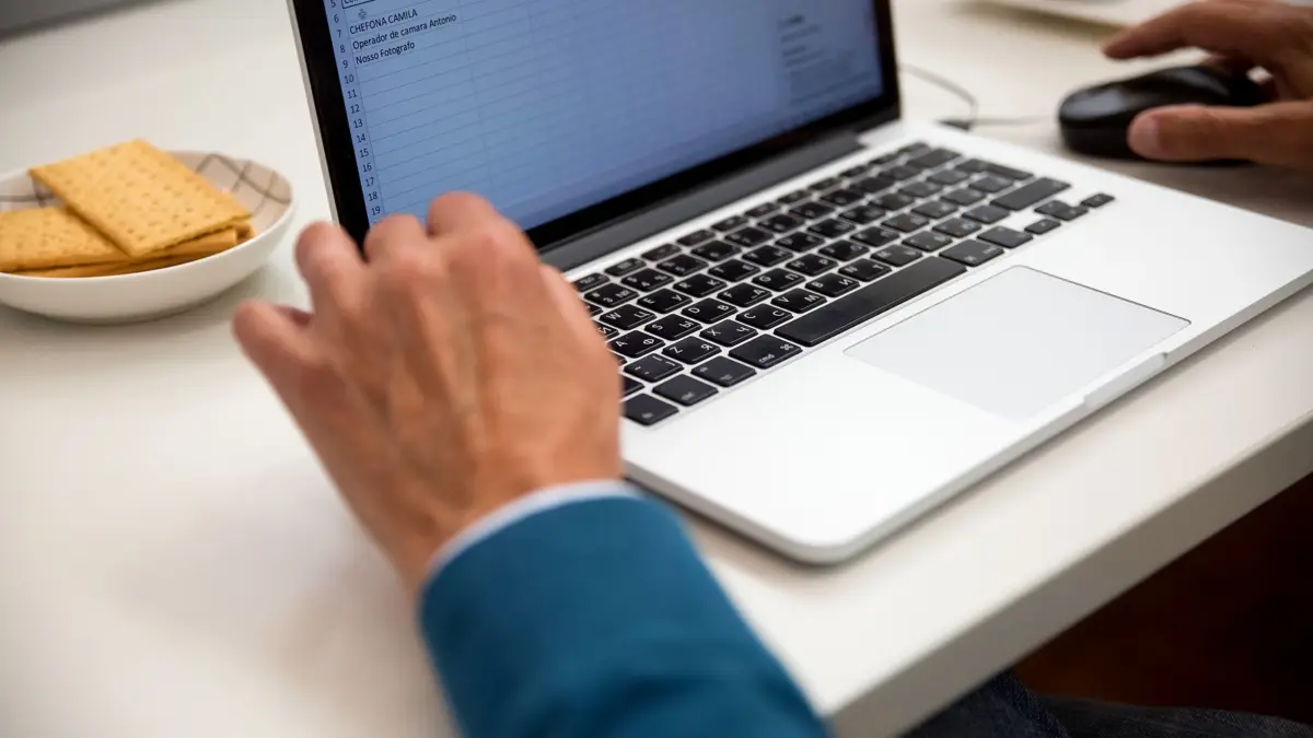 Osoba pracująca na laptopie przy biurku z arkuszem danych