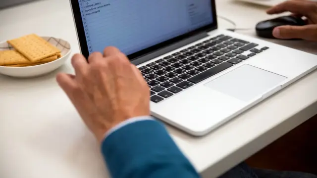 Osoba pracująca na laptopie przy biurku z arkuszem danych