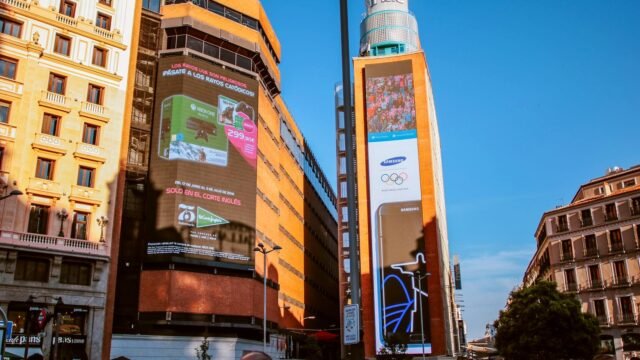 Ulica z dużymi ekranami reklamowymi na ścianach kamienic