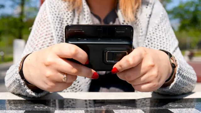 Zbliżenie na dłonie trzymające smartfona z odtwarzanym filmem