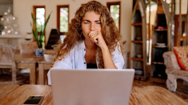 Kobieta czyta wiadomości na laptopie i zastanawia się nad tym, co widzi