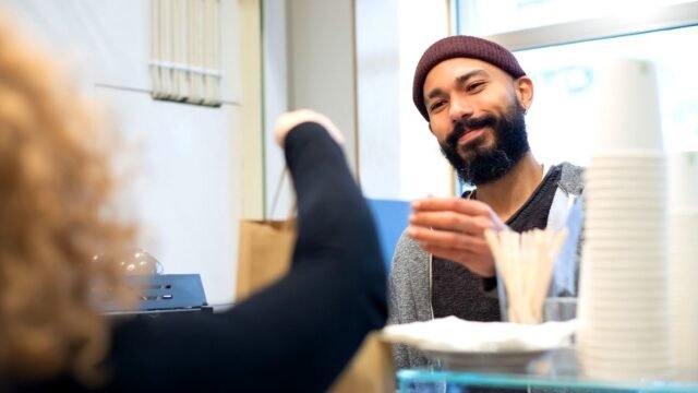 Barista podaje zamówienie klientowi przy ladzie w kawiarni