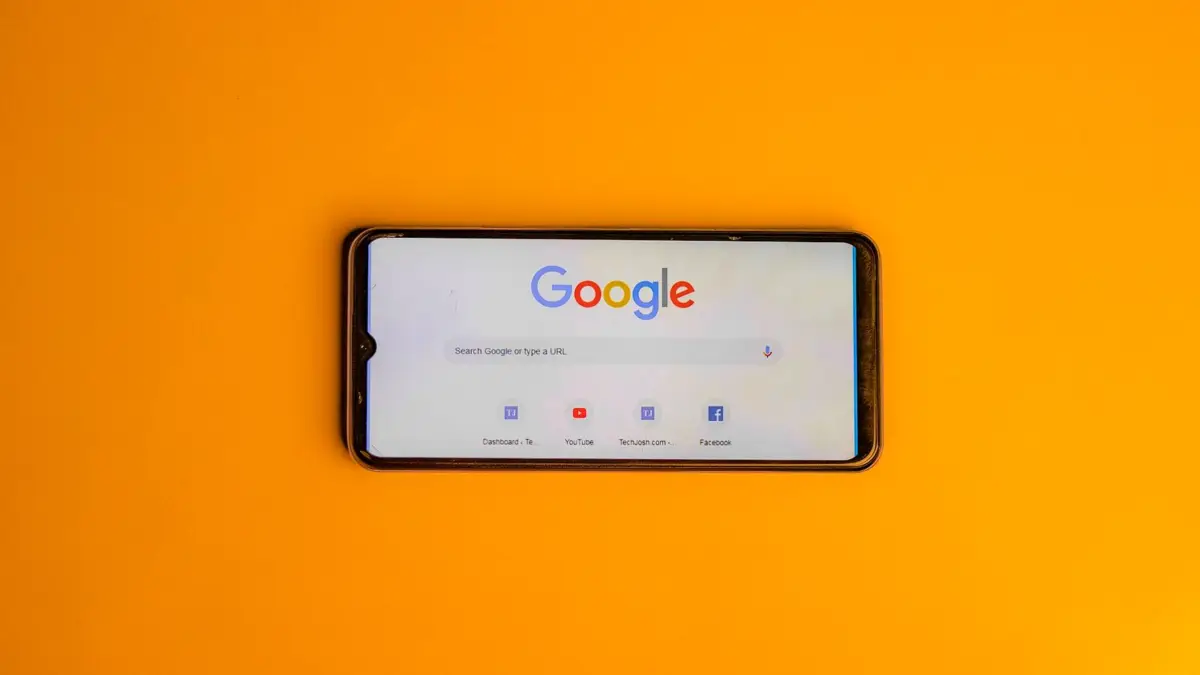 Smartfon ze stroną główną wyszukiwarki Google leży na pomarańczowym tle
