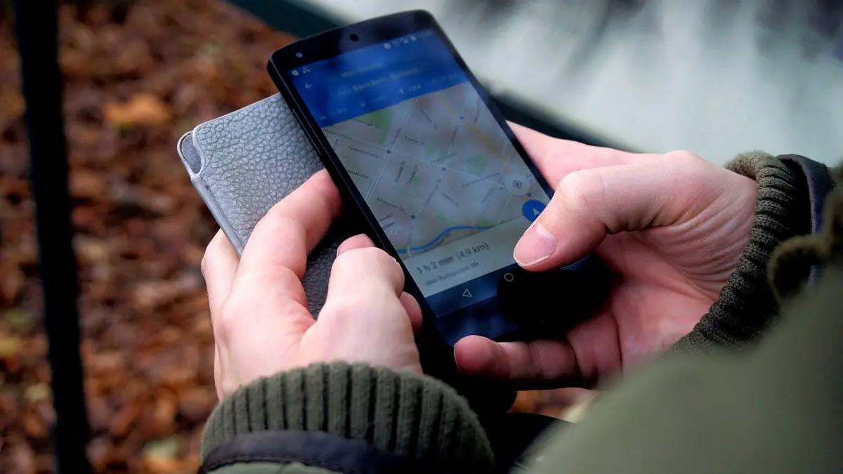 Dłonie trzymające smartfon z otwartą mapą na ulicy