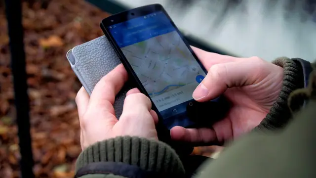 Dłonie trzymające smartfon z otwartą mapą na ulicy