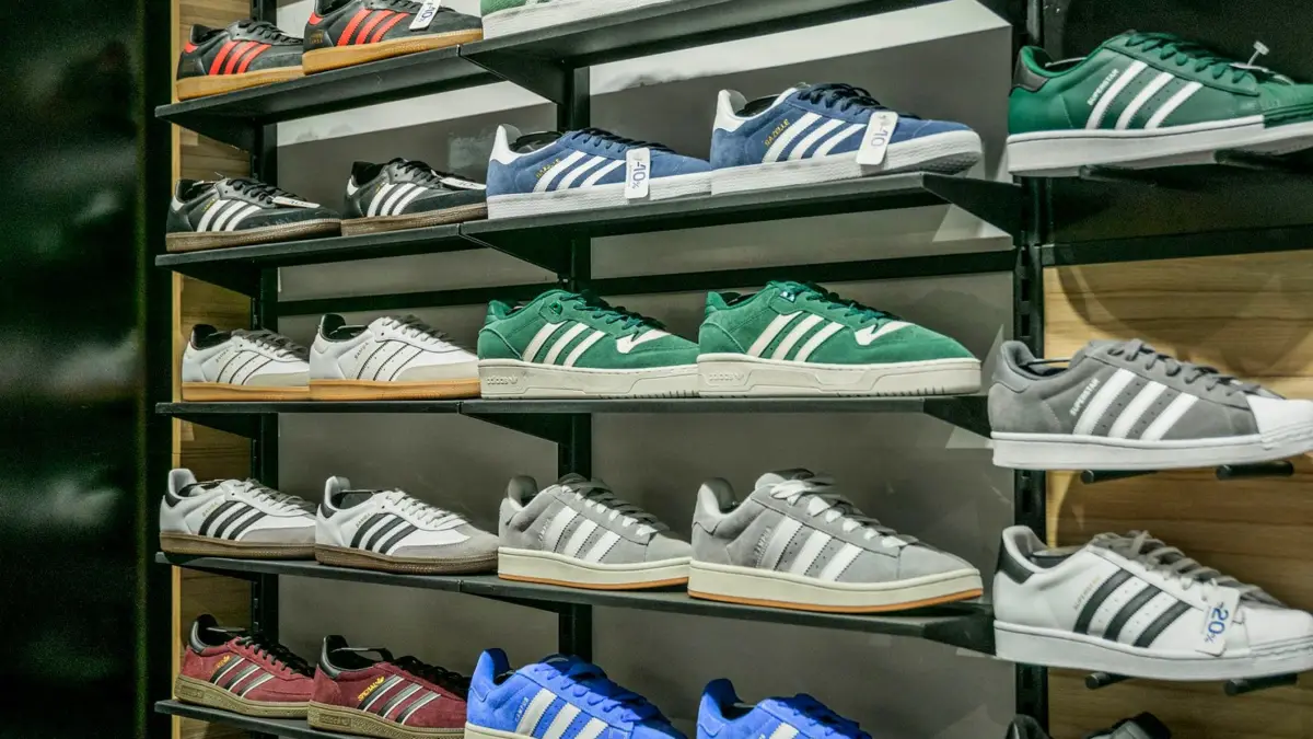 Kolorowe buty sportowe ułożone rzędami na sklepowych półkach.