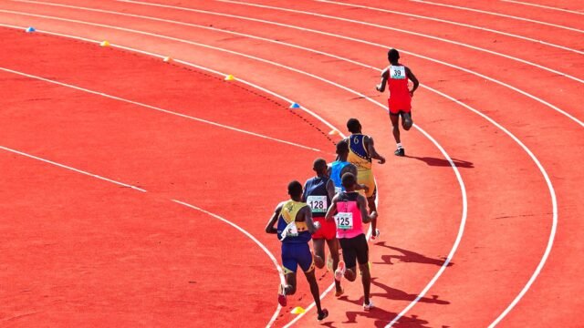 Grupa biegaczy na wirażu bieżni lekkoatletycznej w słoneczny dzień