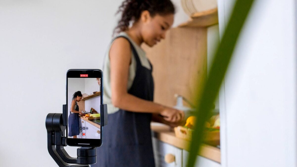 Kobieta nagrywa telefonem na stabilizatorze poradnik kulinarny w nowoczesnej kuchni.