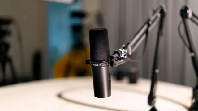 Mikrofon w studiu radiowym, w tle pulpit realizatora
