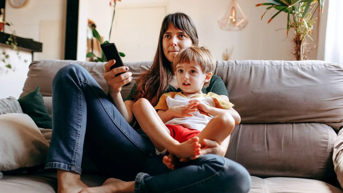 Matka z synem oglądają telewizję na kanapie w salonie