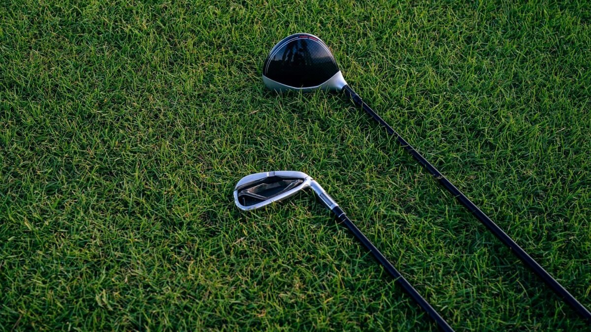 Zbliżenie dwóch kijów golfowych leżących na przystrzyżonej trawie.