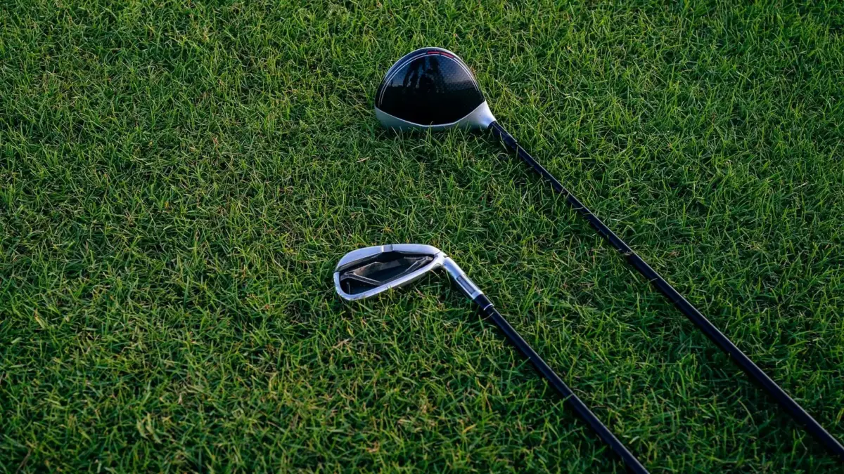 Zbliżenie dwóch kijów golfowych leżących na przystrzyżonej trawie.