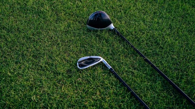 Zbliżenie dwóch kijów golfowych leżących na przystrzyżonej trawie.