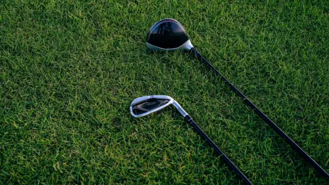 Zbliżenie dwóch kijów golfowych leżących na przystrzyżonej trawie.