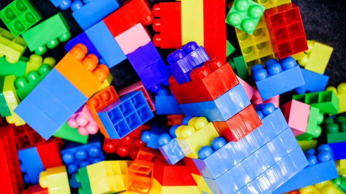 Kolorowe plastikowe klocki ułożone na białym stole.
