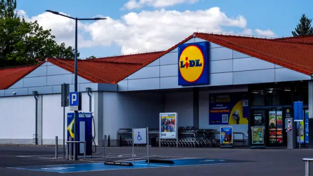Sklep Lidl widziany z parkingu, przy wejściu stoją wózki