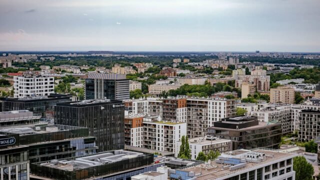 Widok z lotu ptaka na Warszawę z nowoczesną i mieszkaniową zabudową wśród zieleni.