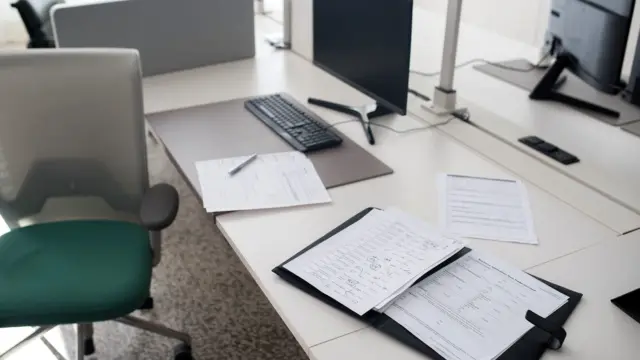 Uporządkowane biurko z dokumentami, laptopem i notesem w jasnym biurze.