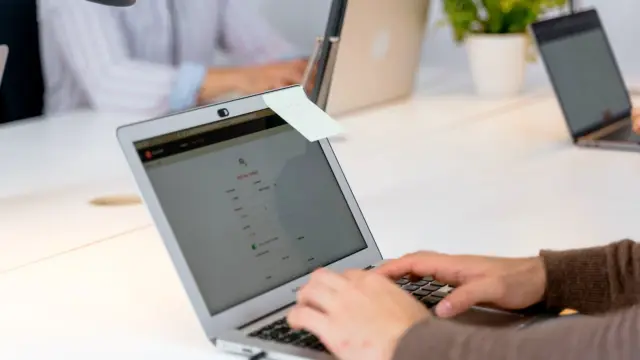Zbliżenie na dłonie osoby pracującej na laptopie przy biurku