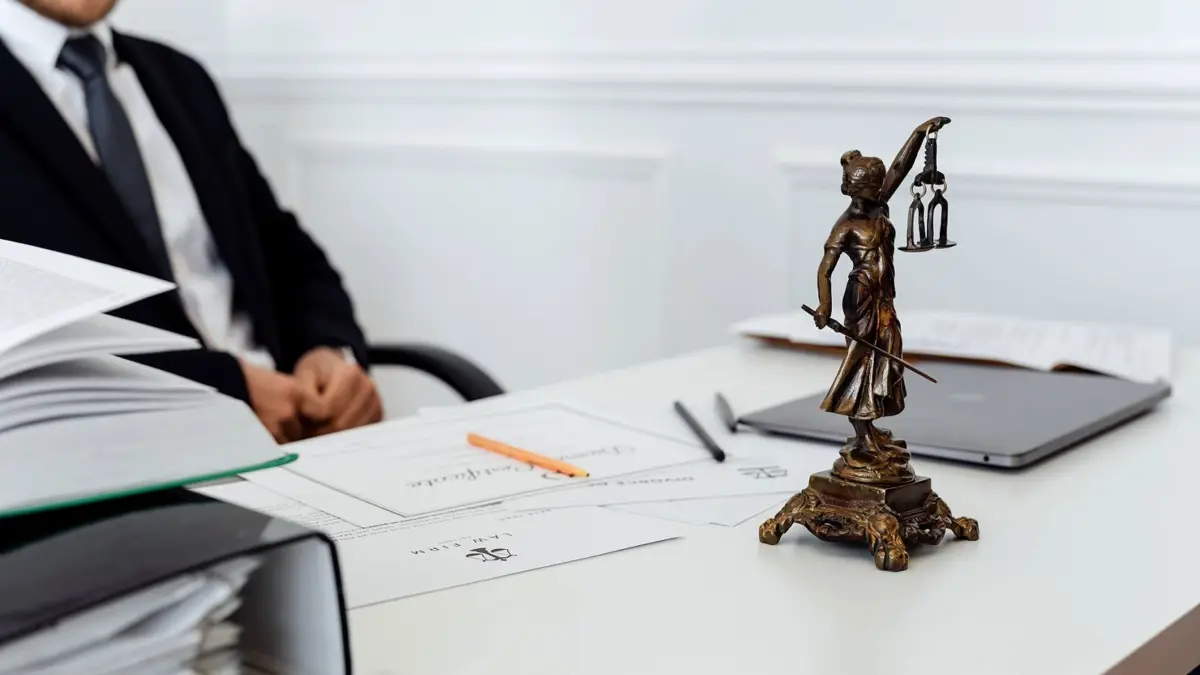 Biurko prawnika z figurką Temidy, dokumentami i laptopem