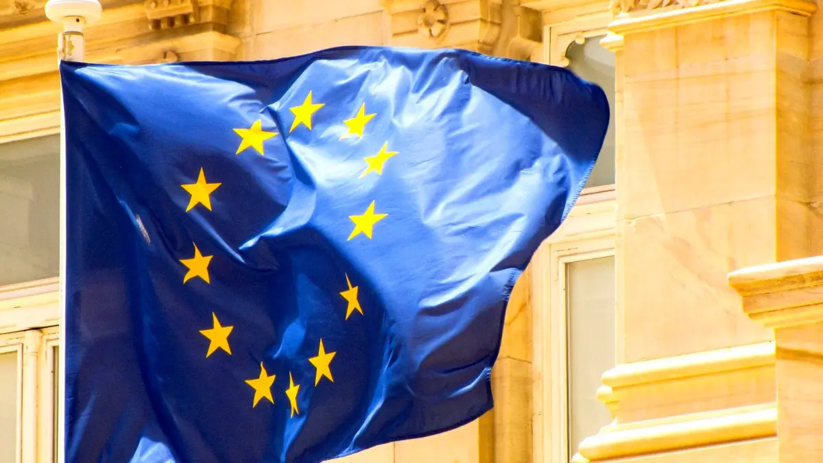 Flaga Unii Europejskiej na maszcie na tle zabytkowej kamienicy