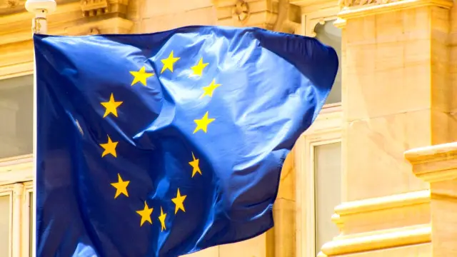 Flaga Unii Europejskiej na maszcie na tle zabytkowej kamienicy