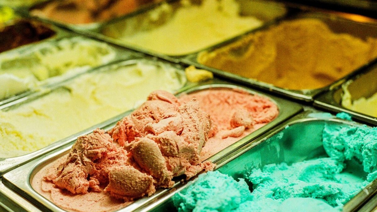 Zbliżenie na lody w kilku smakach w witrynie lodziarni.