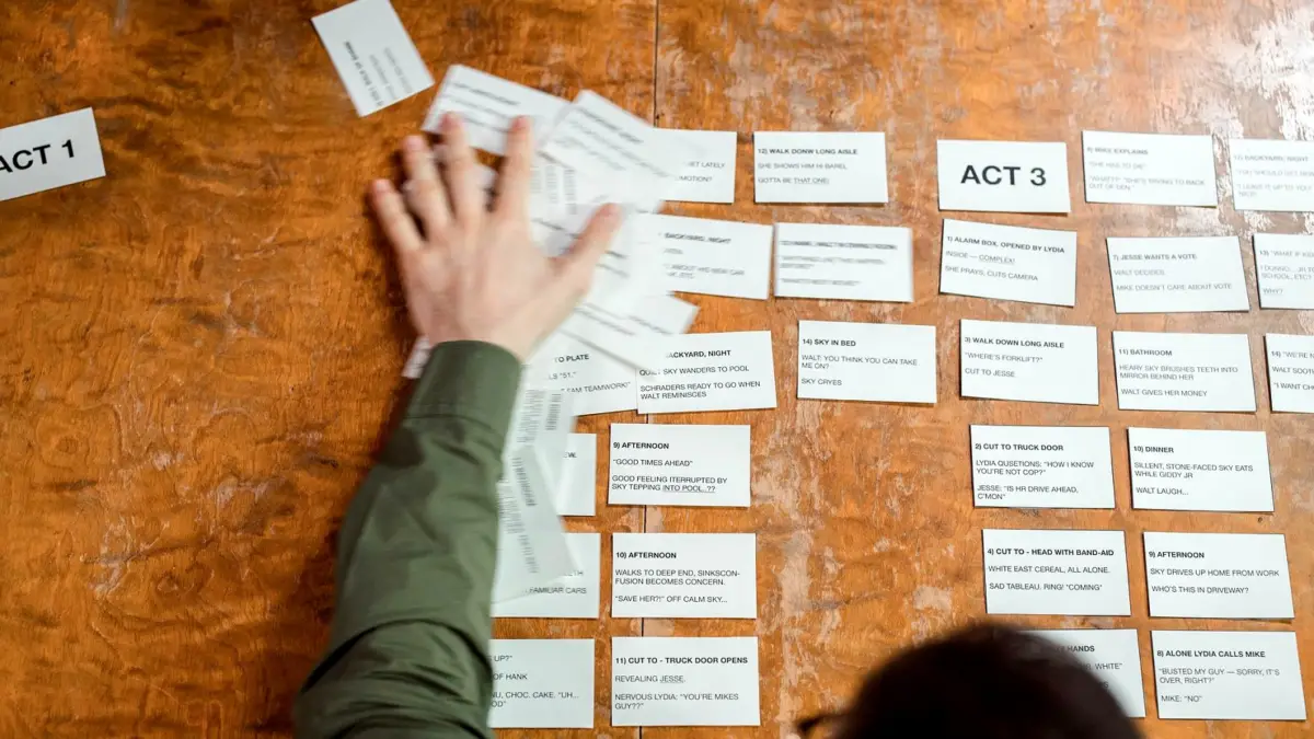 Dłonie układają karty ze scenariuszem reklamy na drewnianym stole