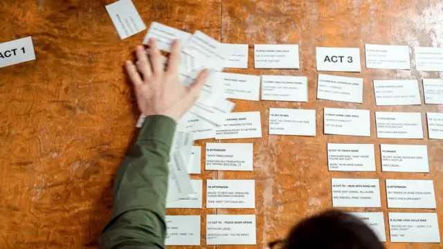 Dłonie układają karty ze scenariuszem reklamy na drewnianym stole