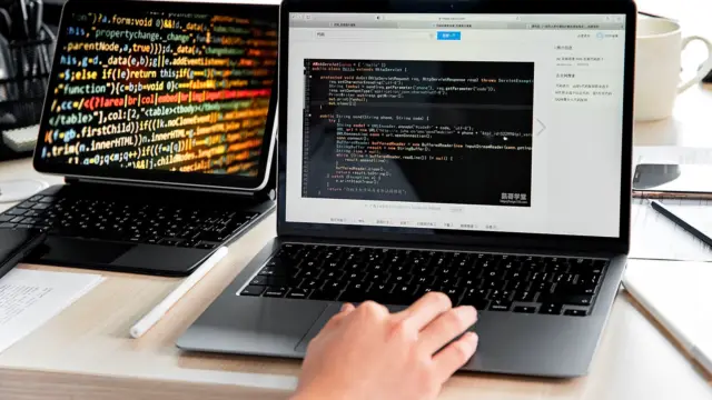 Programista pisze kod na laptopie przy biurku