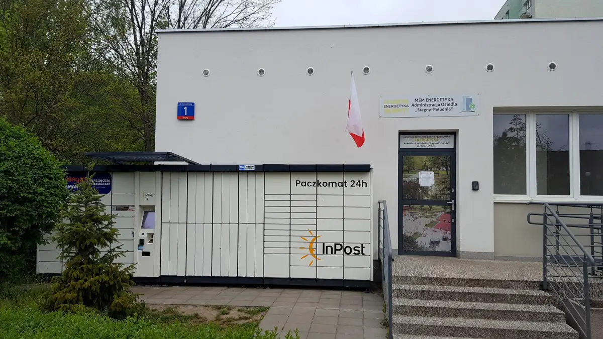 Biały paczkomat InPost przy budynku na warszawskich Stegnach, obok wejście i schody