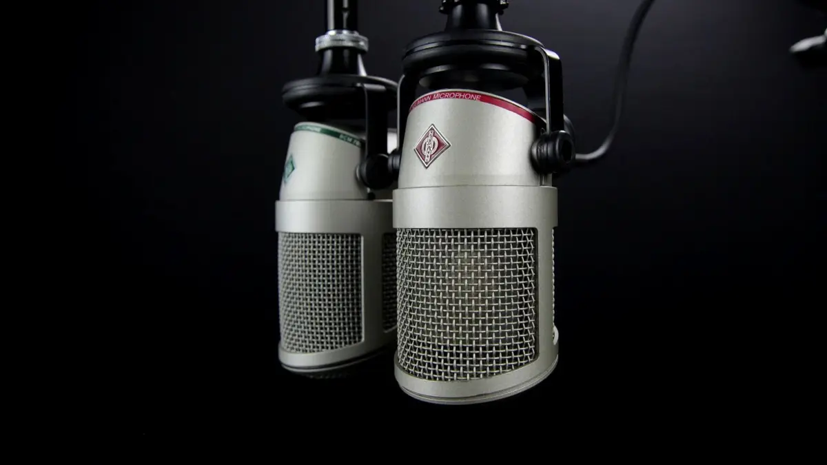 Dwa mikrofony na wysięgnikach w studiu radiowym