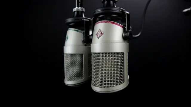 Dwa mikrofony na wysięgnikach w studiu radiowym