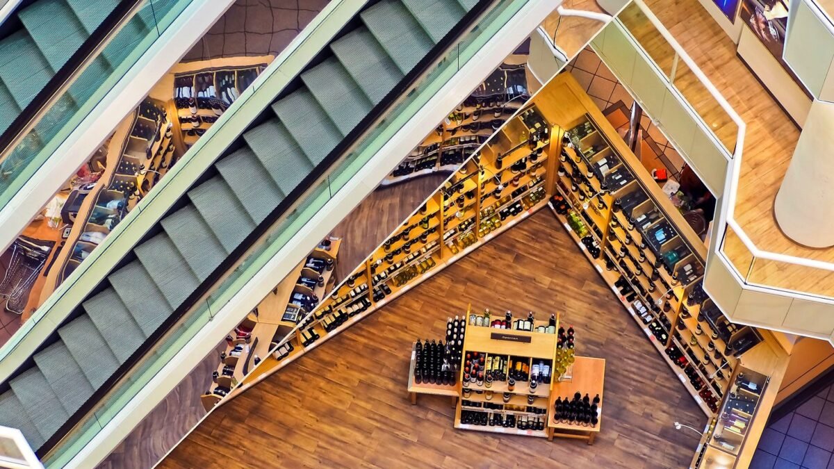 Widok z góry na galerię handlową ze schodami ruchomymi i witrynami sklepów.