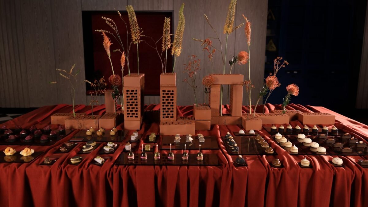 Bufet Royal Catering: jesienne przekąski na czarnych tacach, ceglane kompozycje z suszonymi kwiatami na rdzawej tkaninie