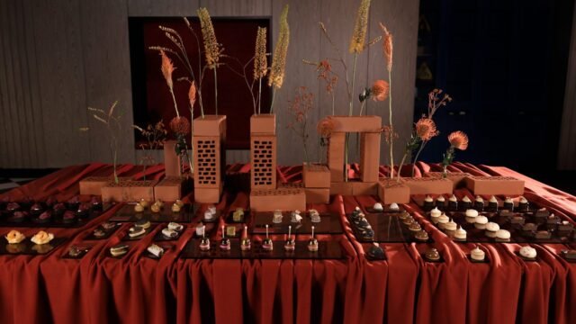 Bufet Royal Catering: jesienne przekąski na czarnych tacach, ceglane kompozycje z suszonymi kwiatami na rdzawej tkaninie