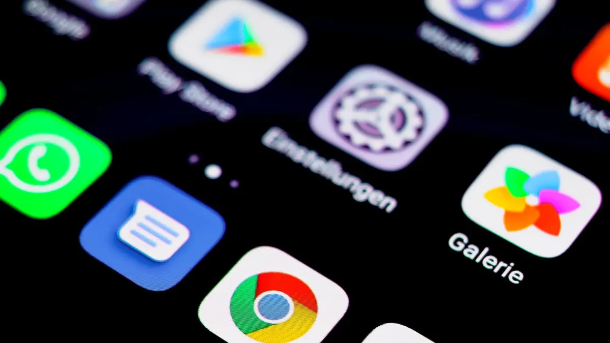 Zbliżenie na ekran smartfona z rzędami ikon aplikacji, telefon trzymany w dłoni.