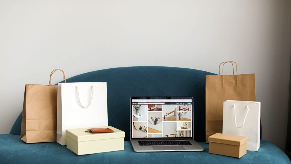 Laptop z otwartym sklepem internetowym, obok papierowe torby na zakupy