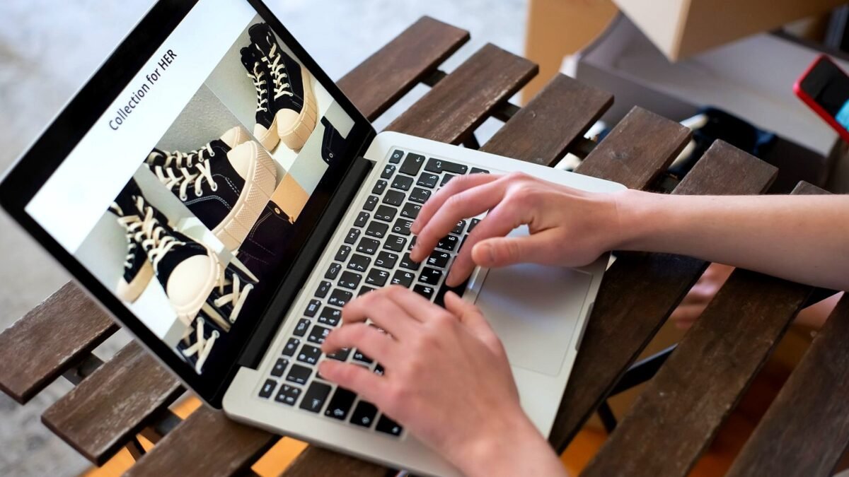 Ręce przeglądające kolekcję ubrań w sklepie internetowym na laptopie