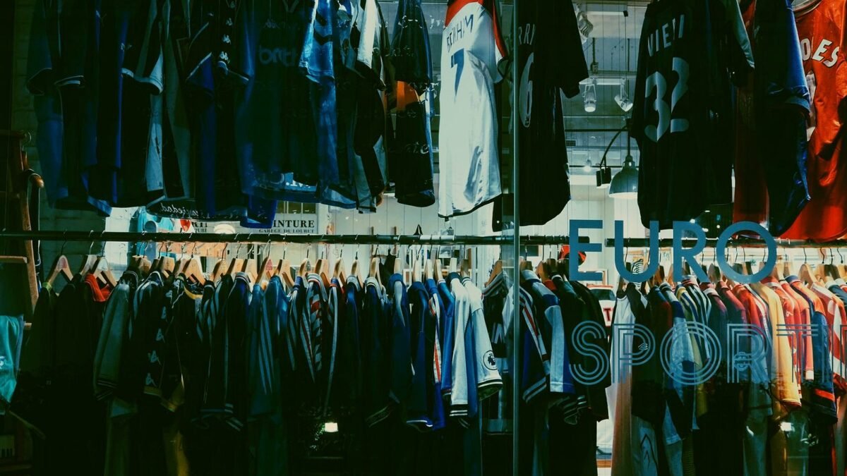 Wieszaki z odzieżą sportową i buty na wystawie w sklepie