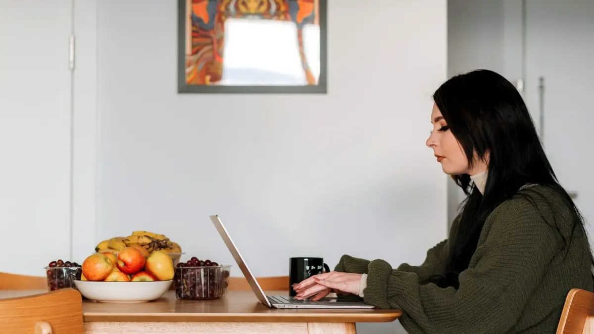 Kobieta przy laptopie w kuchni zamawia zakupy spożywcze