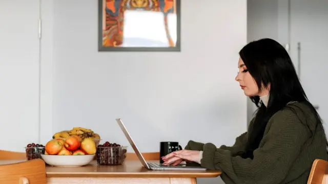 Kobieta przy laptopie w kuchni zamawia zakupy spożywcze