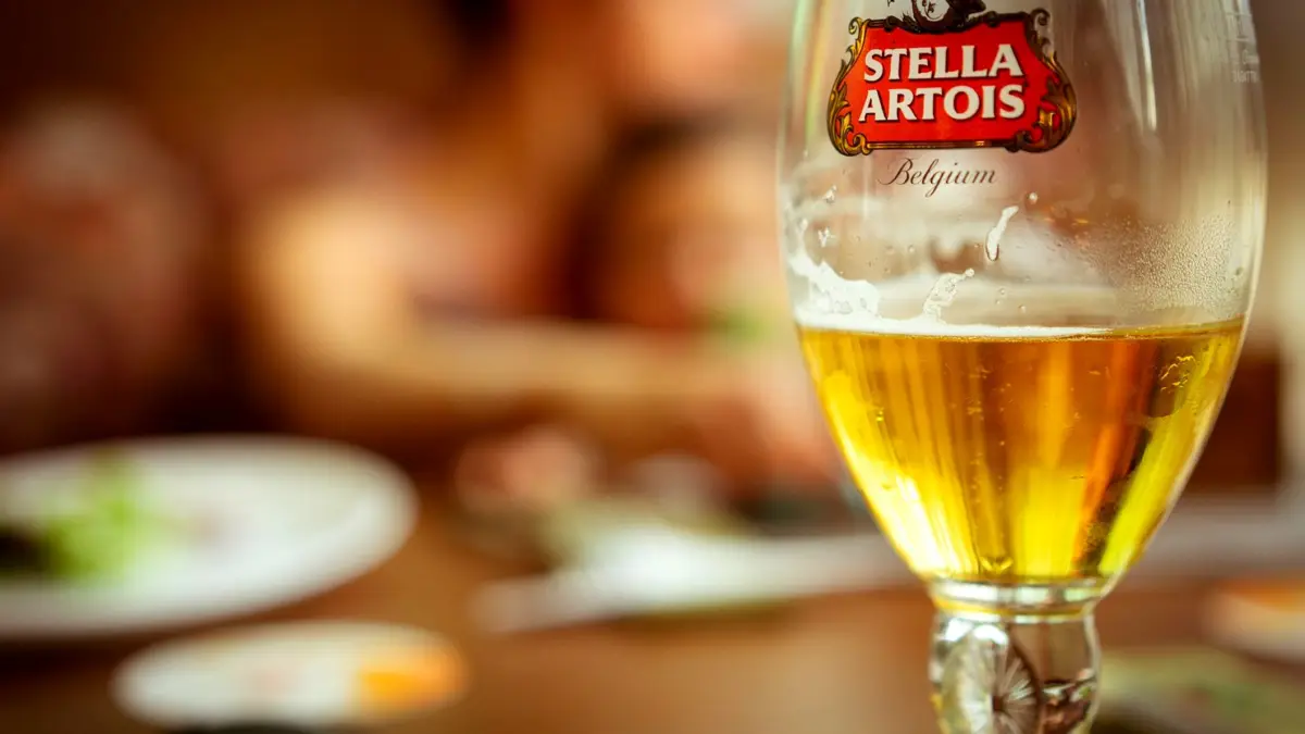 Szklanka piwa Stella Artois z logo marki na stole w pubie