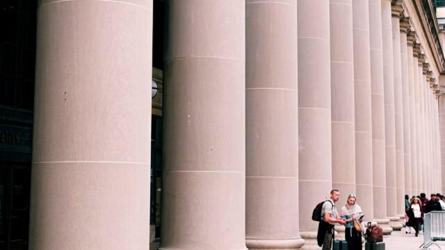 Dwoje podróżnych stoi przy masywnych kolumnach budynku w Chicago.