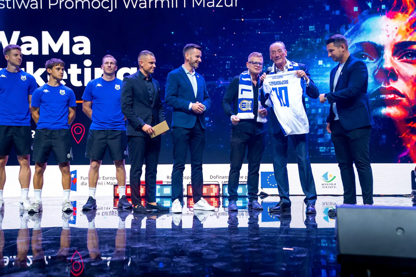 Wręczenie koszulki Stomilu Olsztyn Dariuszowi Szpakowskiemu na scenie konferencji #WaMaMarketing